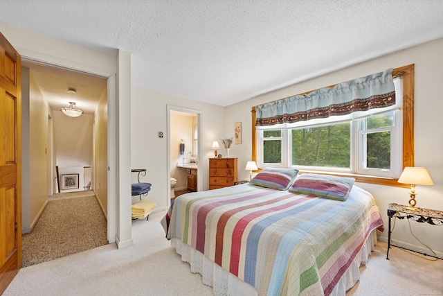 bedroom featuring carpet, a textured ceiling, and ensuite bathroom
