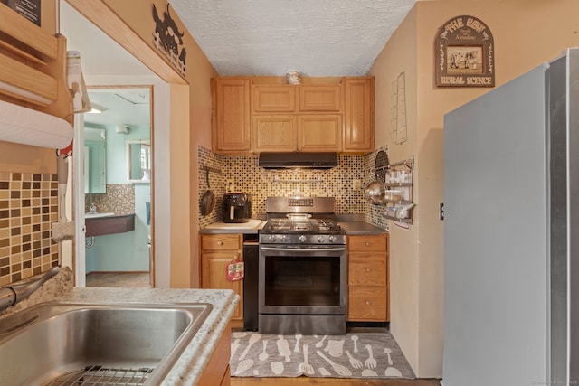 53 Columbus Ave, Bristol, CT 06010 - kitchen with freestanding refrigerator, stainless steel range with gas cooktop, under cabinet range hood, backsplash, and a textured ceiling