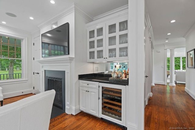 206 Fox Hopyard Rd, East Haddam, CT 06423 - indoor wet bar featuring beverage cooler, dark wood finished floors, ornamental molding, recessed lighting, and a fireplace