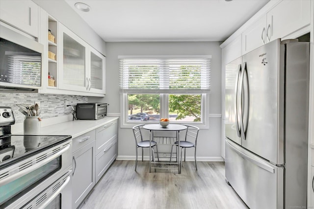 16 Juniper Cir Unit 16, Monroe, CT 06468 - kitchen with stainless steel appliances, light wood finished floors, tasteful backsplash, glass insert cabinets, and light countertops