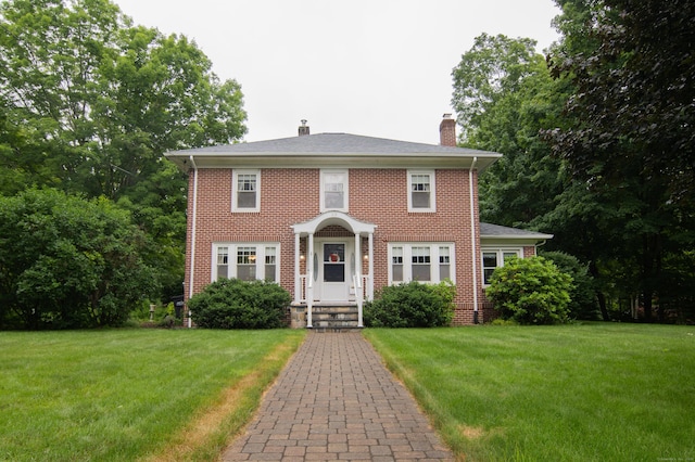 23 E St, Stafford, CT 06076 - colonial-style house with a chimney, a front lawn, and brick siding