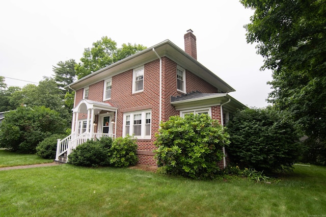 23 E St, Stafford, CT 06076 - view of front of property featuring a chimney, a front lawn, and brick siding