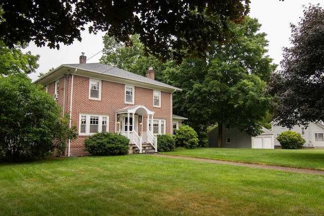 23 E St, Stafford, CT 06076 - american foursquare style home featuring a chimney, brick siding, a front yard, and a garage