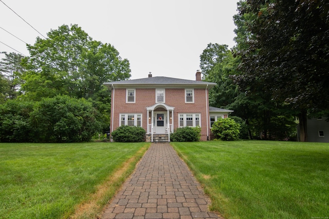 23 E St, Stafford, CT 06076 - colonial home featuring a chimney, brick siding, and a front yard