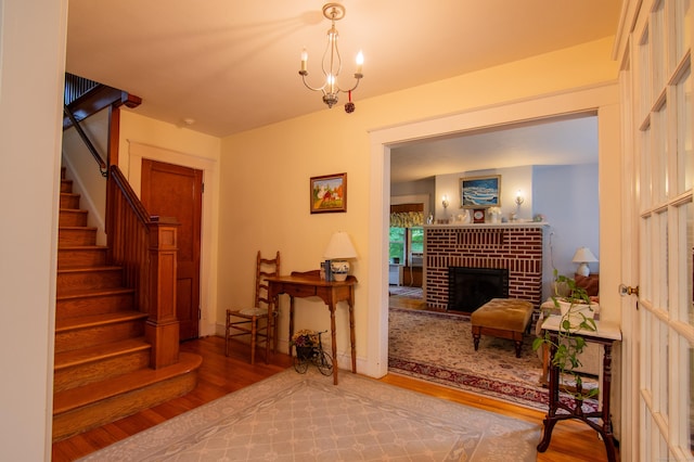23 E St, Stafford, CT 06076 - entryway featuring wood finished floors, stairway, a brick fireplace, and a chandelier
