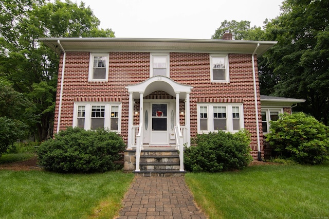 23 E St, Stafford, CT 06076 - view of front of house featuring a front yard, a chimney, and brick siding