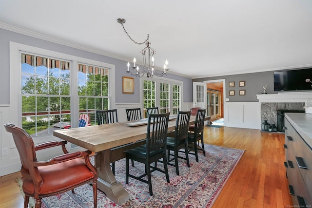 101 Golden Hill St, Trumbull, CT 06611 - dining space with ornamental molding, a chandelier, a wainscoted wall, light wood-style flooring, and a fireplace