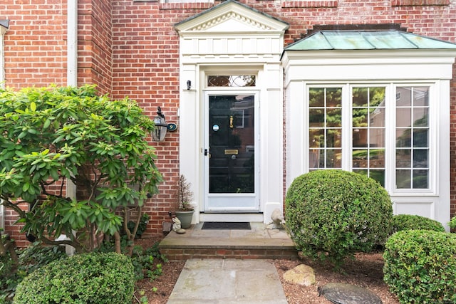 312 Elm St Apt 9, New Canaan, CT 06840 - view of exterior entry featuring brick siding and a standing seam roof