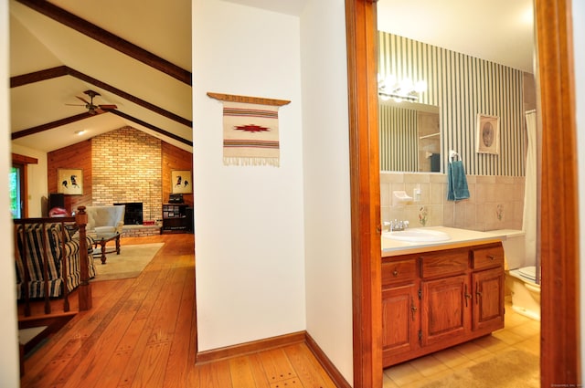 172 Bentley Cir, Goshen, CT 06756 - bathroom featuring ceiling fan, vanity, wood-type flooring, a brick fireplace, and tasteful backsplash