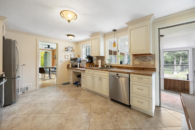 931 Chestnut Hill Rd, Glastonbury, CT 06073 - kitchen with cream cabinetry, stainless steel appliances, backsplash, light tile patterned floors, and decorative light fixtures