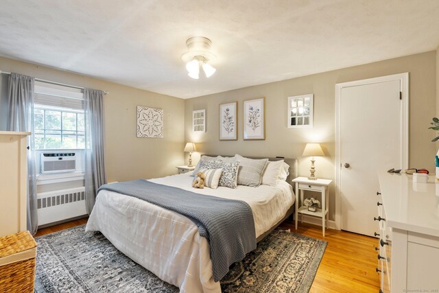216 Main St, Glastonbury, CT 06073 - bedroom with radiator heating unit, cooling unit, and light wood-style floors