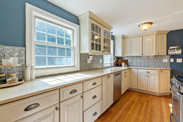 216 Main St, Glastonbury, CT 06073 - kitchen featuring appliances with stainless steel finishes, light countertops, tasteful backsplash, light wood-type flooring, and glass insert cabinets