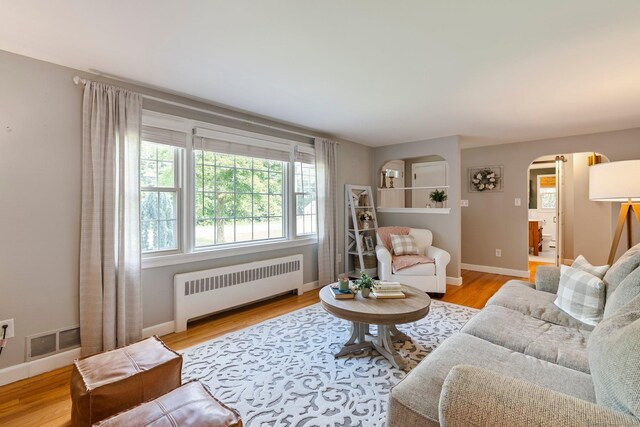216 Main St, Glastonbury, CT 06073 - living area featuring radiator heating unit, arched walkways, and light wood-type flooring