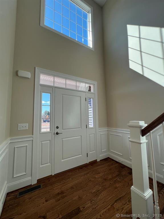 44 Primrose Ln, Cromwell, CT 06416 - foyer entrance featuring a high ceiling, dark wood finished floors, wainscoting, a decorative wall, and stairway