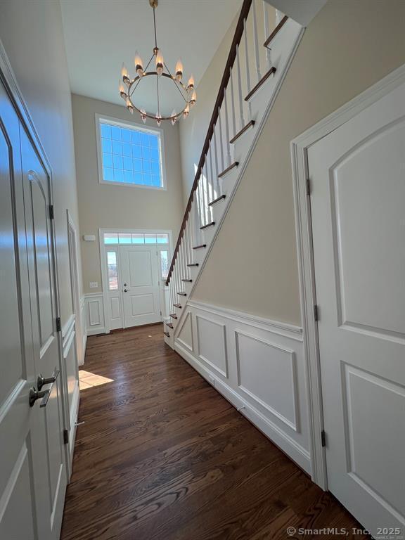 44 Primrose Ln, Cromwell, CT 06416 - foyer with a chandelier, stairway, dark wood-type flooring, a decorative wall, and wainscoting