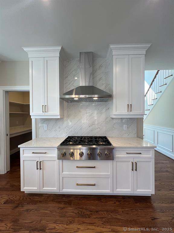 44 Primrose Ln, Cromwell, CT 06416 - kitchen featuring wall chimney range hood, stainless steel gas stovetop, light stone counters, and white cabinetry