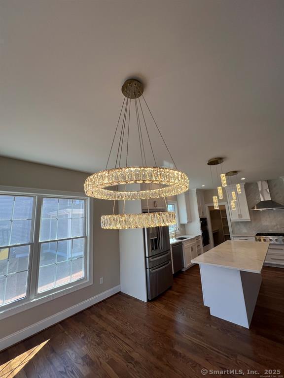 44 Primrose Ln, Cromwell, CT 06416 - kitchen with wall chimney exhaust hood, dark wood finished floors, a kitchen island, hanging light fixtures, and plenty of natural light