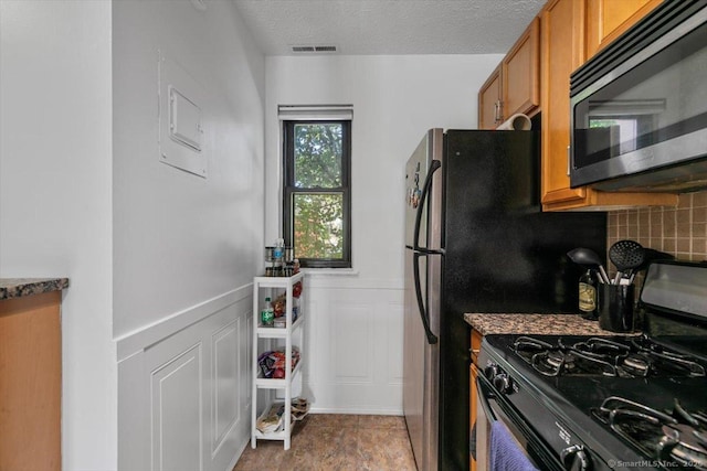 125 Olive St Apt D2, New Haven, CT 06511 - kitchen with gas range, stainless steel microwave, brown cabinetry, tasteful backsplash, and a wainscoted wall