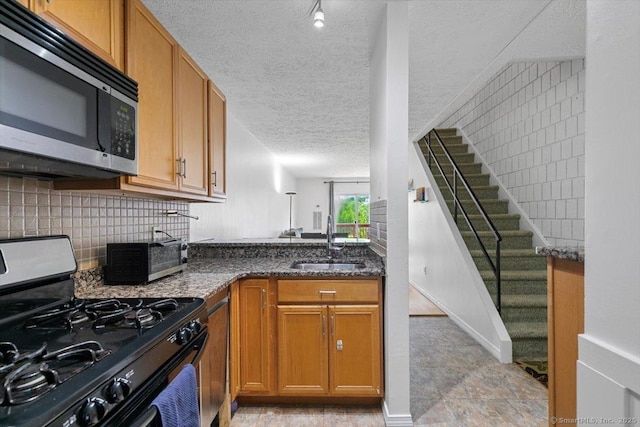 125 Olive St Apt D2, New Haven, CT 06511 - kitchen featuring stainless steel appliances, decorative backsplash, a textured ceiling, brown cabinets, and dark stone counters
