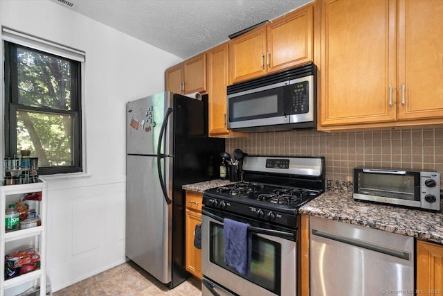 125 Olive St Apt D2, New Haven, CT 06511 - kitchen with stainless steel appliances, decorative backsplash, dark stone countertops, and brown cabinets