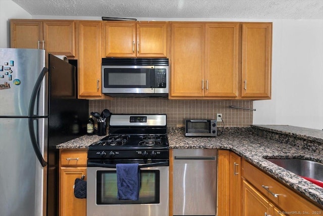 125 Olive St Apt D2, New Haven, CT 06511 - kitchen featuring appliances with stainless steel finishes, decorative backsplash, brown cabinetry, dark stone countertops, and a textured ceiling