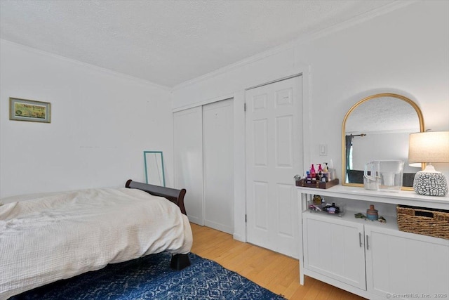 125 Olive St Apt D2, New Haven, CT 06511 - bedroom with ornamental molding, light wood-style flooring, a textured ceiling, and a closet