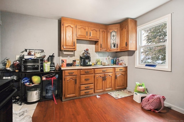 32 Williams St, Bristol, CT 06010 - kitchen featuring light countertops, dark wood finished floors, decorative backsplash, and brown cabinets