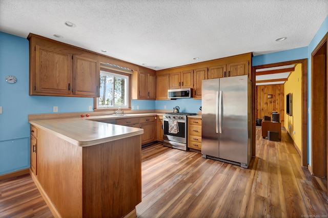 186 Wood Pond Rd, South Windsor, CT 06074 - kitchen with appliances with stainless steel finishes, a peninsula, light wood-type flooring, light countertops, and a textured ceiling