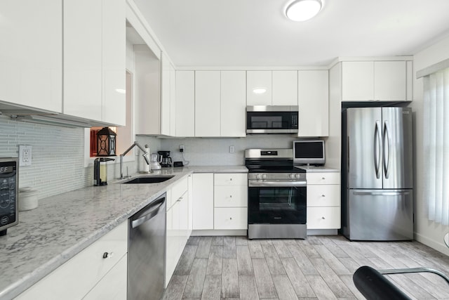 376 Woodridge Unit 376, Shelton, CT 06484 - kitchen featuring stainless steel appliances, light wood finished floors, white cabinetry, tasteful backsplash, and light stone countertops