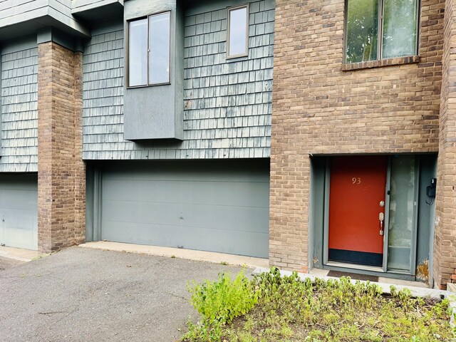 93 Trolley Crossing Ln Unit 93, Middletown, CT 06457 - view of exterior entry featuring a garage, asphalt driveway, and brick siding