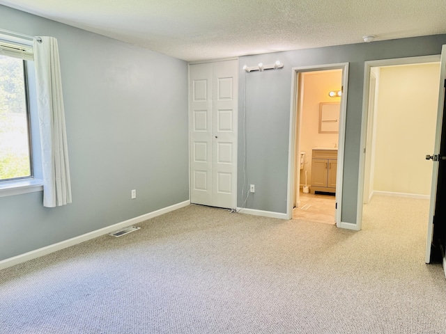 93 Trolley Crossing Ln Unit 93, Middletown, CT 06457 - unfurnished bedroom with carpet, multiple windows, a textured ceiling, and connected bathroom