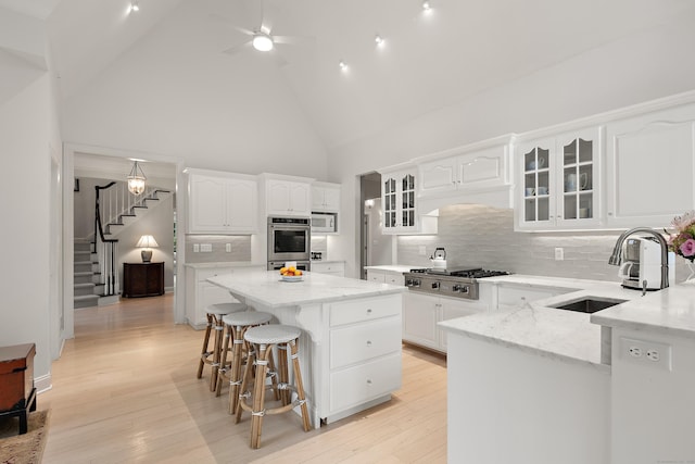 7 Merlins Ln, Newtown, CT 06470 - kitchen featuring stainless steel gas cooktop, high vaulted ceiling, a kitchen island, glass insert cabinets, and white cabinets