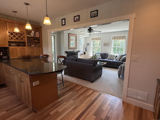 5 Lees Ct, Stonington, CT 06378 - kitchen featuring wood finished floors, a breakfast bar, brown cabinets, and pendant lighting