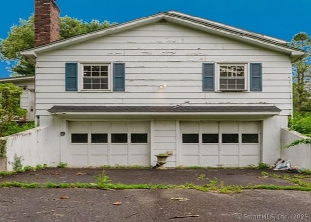 2 Rolf Dr, Danbury, CT 06810 - view of side of property with an attached garage, a chimney, and asphalt driveway