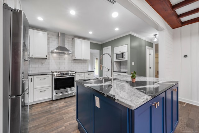 16 Pine Rd, Stafford, CT 06076 - kitchen featuring wall chimney range hood, stainless steel appliances, blue cabinets, decorative backsplash, and dark wood finished floors