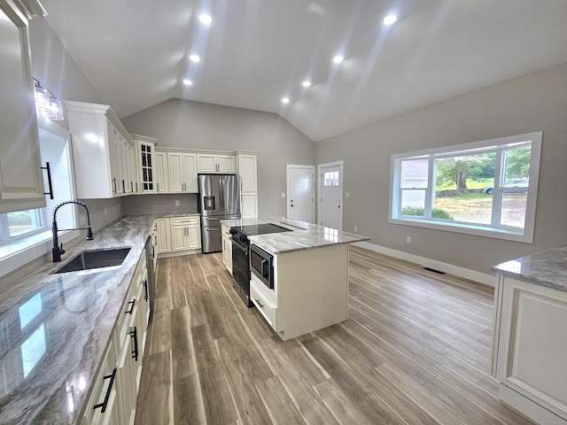 203 Old Jewett City Rd, Preston, CT 06365 - kitchen with appliances with stainless steel finishes, a kitchen island, vaulted ceiling, light stone countertops, and glass insert cabinets