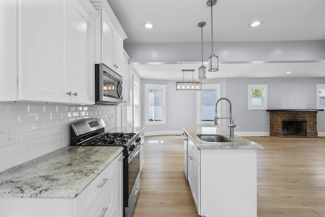 476 Washington Ave, West Haven, CT 06516 - kitchen featuring stainless steel appliances, a fireplace, open floor plan, light wood finished floors, and white cabinetry