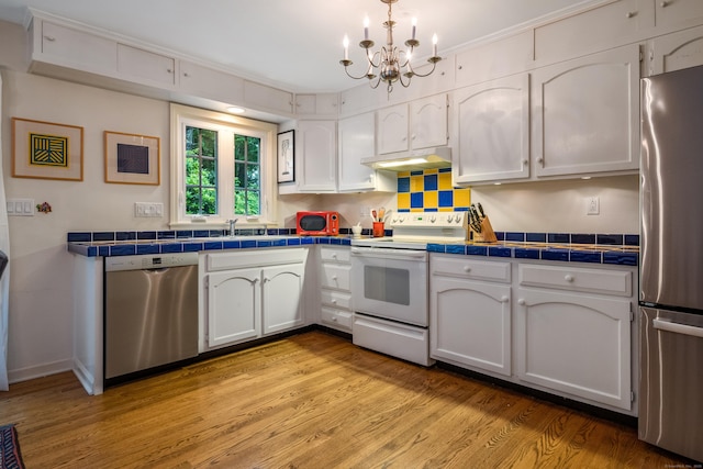 65 Main St Unit 39, Essex, CT 06442 - kitchen with appliances with stainless steel finishes, tile counters, white cabinets, and a chandelier