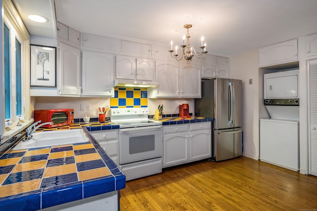 65 Main St Unit 39, Essex, CT 06442 - kitchen featuring white electric range oven, freestanding refrigerator, stacked washer / dryer, tile counters, and under cabinet range hood