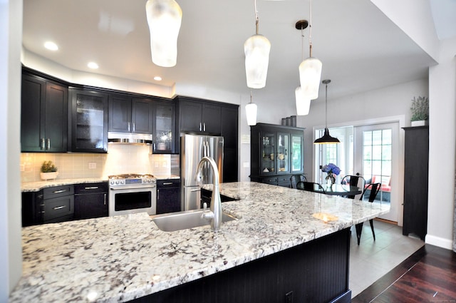 419 Briarwood Dr, Manchester, CT 06040 - kitchen featuring appliances with stainless steel finishes, under cabinet range hood, glass insert cabinets, decorative backsplash, and hanging light fixtures