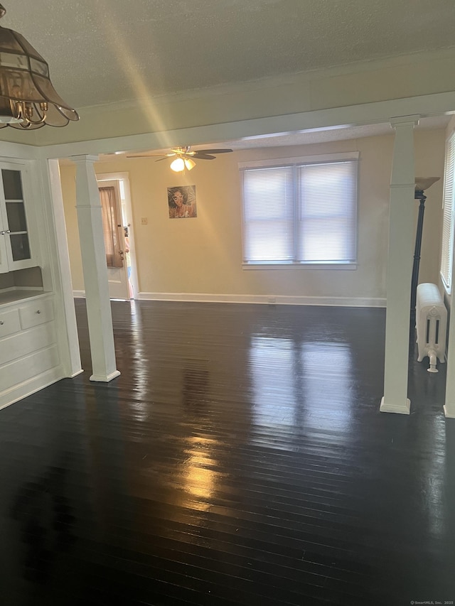 24 Daniel St, East Hartford, CT 06108 - unfurnished living room featuring dark wood-type flooring, a ceiling fan, ornate columns, ornamental molding, and a textured ceiling