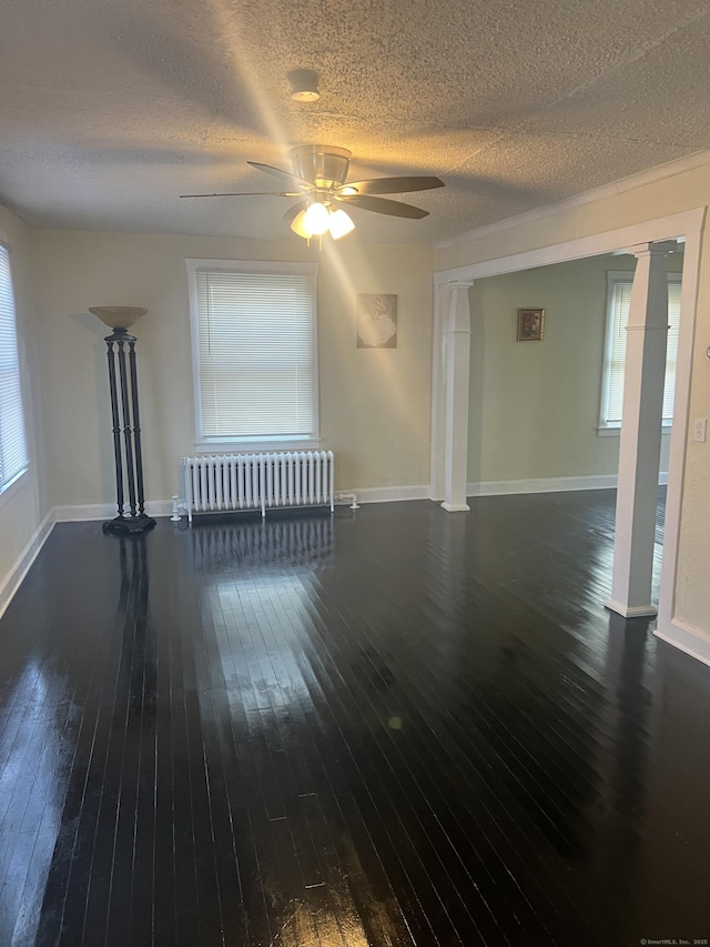 24 Daniel St, East Hartford, CT 06108 - unfurnished living room with radiator heating unit, decorative columns, hardwood / wood-style floors, and a textured ceiling