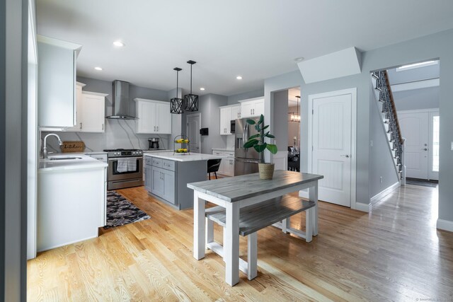 11 Mariani Dr, Southington, CT 06489 - kitchen featuring appliances with stainless steel finishes, wall chimney exhaust hood, light countertops, a kitchen island, and white cabinets