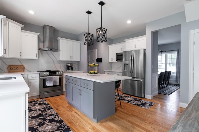 11 Mariani Dr, Southington, CT 06489 - kitchen featuring stainless steel appliances, wall chimney range hood, light countertops, a kitchen island, and light wood-style flooring