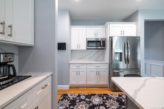 11 Mariani Dr, Southington, CT 06489 - kitchen with stainless steel appliances, light wood-style floors, light stone counters, white cabinets, and tasteful backsplash