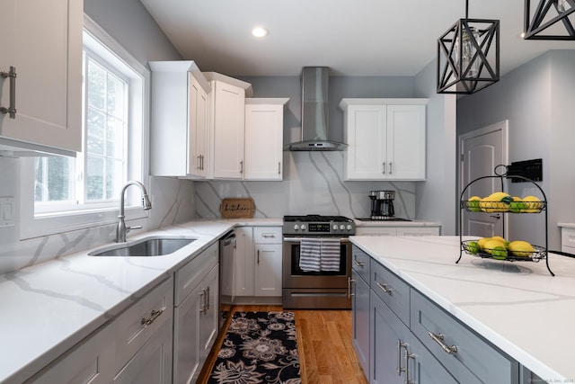 11 Mariani Dr, Southington, CT 06489 - kitchen featuring wall chimney range hood, stainless steel range with gas cooktop, white cabinetry, light wood finished floors, and decorative light fixtures