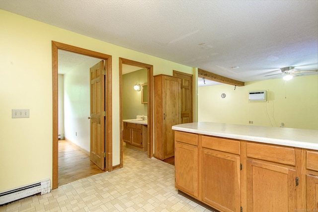 132 Wade Rd, Pomfret, CT 06259 - kitchen with a baseboard heating unit, light countertops, a textured ceiling, a wall mounted air conditioner, and brown cabinetry
