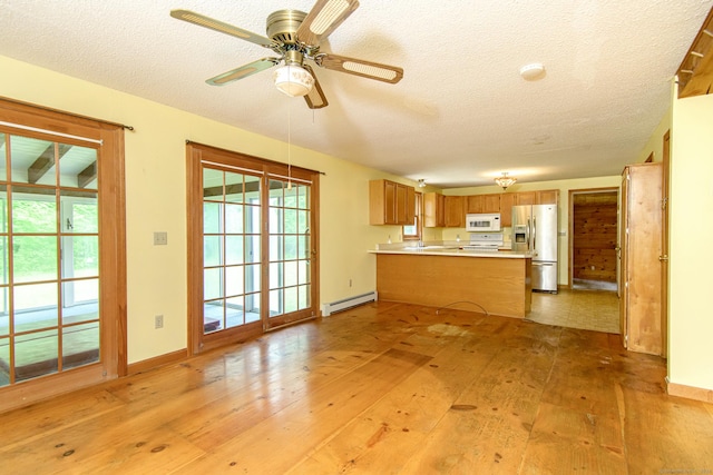 132 Wade Rd, Pomfret, CT 06259 - kitchen featuring stainless steel fridge, white microwave, a baseboard radiator, a peninsula, and a textured ceiling