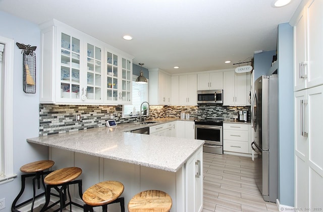 362 Main St, Meriden, CT 06451 - kitchen with appliances with stainless steel finishes, a peninsula, white cabinetry, decorative backsplash, and glass insert cabinets