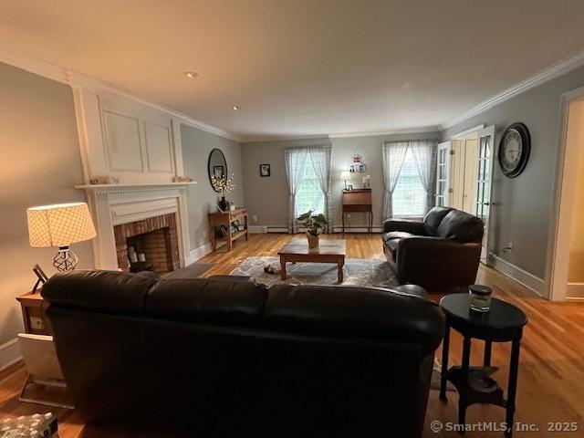 47 Merwin Brook Rd, Brookfield, CT 06804 - living area with crown molding, light wood-style flooring, a brick fireplace, and baseboard heating